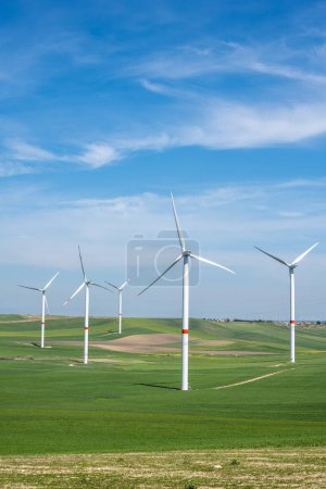 Wind turbines and green agricultural landscape seen in Puglia, Italy