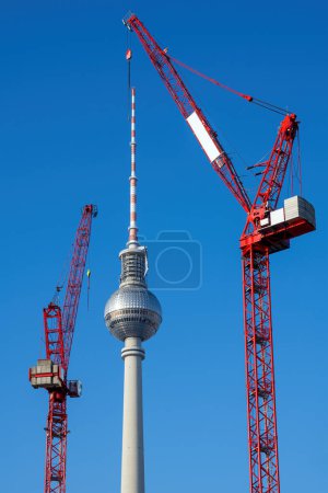 The famous Television Tower of Berlin with two red tower cranes