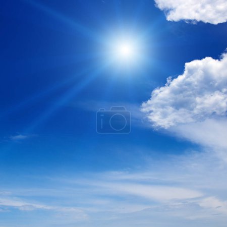 Foto de Bright sun on beautiful blue sky with white fluffy clouds. - Imagen libre de derechos