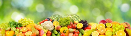 Foto de Delicious fresh vegetables, fruits, vegetables on blurred green background. - Imagen libre de derechos