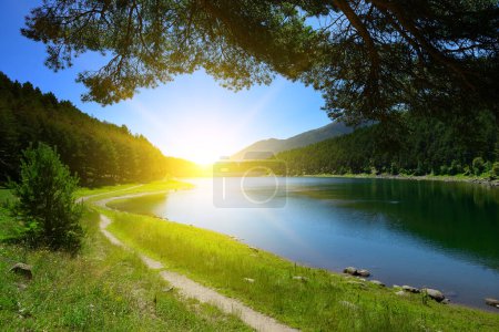 Téléchargez les photos : Beau lever de soleil sur le lac bleu et les montagnes couvertes de forêts de conifères. - en image libre de droit