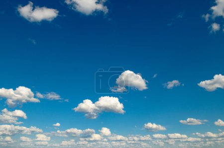 Téléchargez les photos : Nuages blancs pelucheux et soleil brillant sur ciel bleu foncé. - en image libre de droit