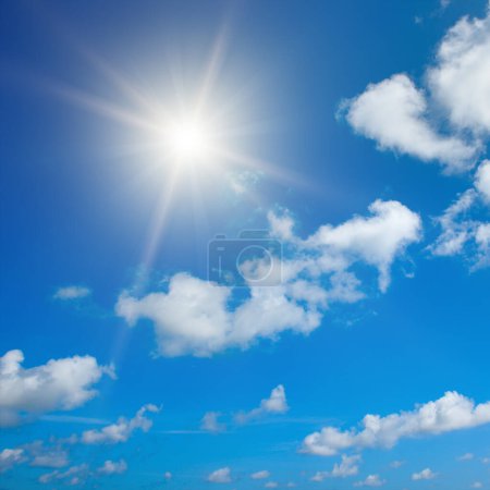 Foto de Bright sun on beautiful blue sky with white fluffy clouds. - Imagen libre de derechos