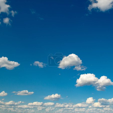 Téléchargez les photos : Nuages blancs pelucheux et soleil brillant sur ciel bleu foncé. - en image libre de droit