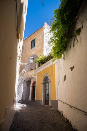Photo for Old historic shabby romantic streets of southern Italy in the city of Amalfi. Narrow vintage streets, turns, doors flooded with summer sun. Middle Ages European tourism. - Royalty Free Image