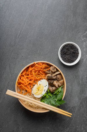 Photo for Noodle soup, ramen in a white bowl (bowl) with chicken egg, carrots, mushrooms on a dark slate stone background. Asian traditional fast food - Royalty Free Image