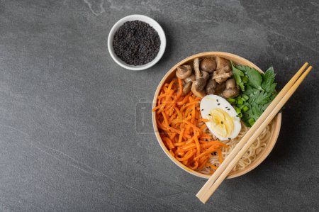 Photo for Noodle soup, ramen in a white bowl (bowl) with chicken egg, carrots, mushrooms on a dark slate stone background. Asian traditional fast food - Royalty Free Image