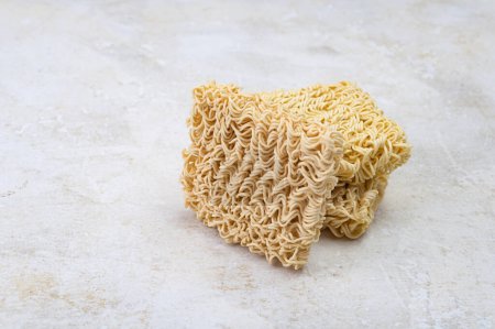 Photo for Square dry egg noodles in a briquette on a light beige stone marble background. Asian fast food. - Royalty Free Image