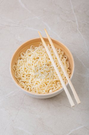 Photo for White bamboo plate (bowl) with egg noodles and chopsticks on a light background. Asian traditional fast food - Royalty Free Image