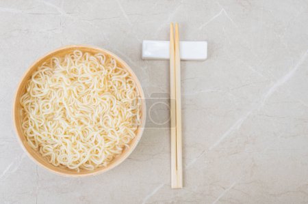 Téléchargez les photos : Assiette en bambou blanc (bol) avec nouilles aux œufs et baguettes sur un fond clair. Asiatique traditionnel fast food - en image libre de droit