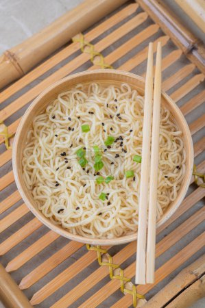 Photo for White bamboo plate (bowl) with egg noodles and plates with ingredients for it on a bamboo serving tray against a light background. Asian traditional fast food - Royalty Free Image