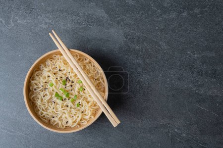Photo for White bamboo plate (bowl) with egg noodles and chopsticks on a dark marble (slate) background. Asian traditional fast food - Royalty Free Image