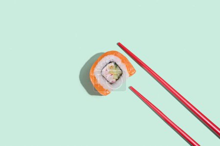 Téléchargez les photos : Sushis au saumon japonais, rouleaux de dragon avec baguettes rouges sur fond vert pastel. Pop art. Alimentation traditionnelle asiatique - en image libre de droit