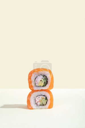 Téléchargez les photos : Une paire de sushis de saumon japonais, dragon roule sur un fond jaune vif. Pop art. Baguettes de snacks savoureux. Alimentation traditionnelle asiatique - en image libre de droit