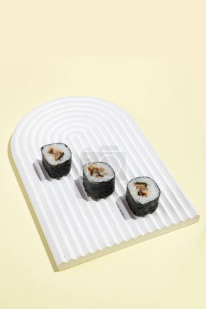 Téléchargez les photos : Culture asiatique, hosomaki japonais (sushi, petits pains) avec anguille sur fond jaune. Cuisine orientale, cuisine orientale. Amuse-gueule savoureux sur le plateau - en image libre de droit