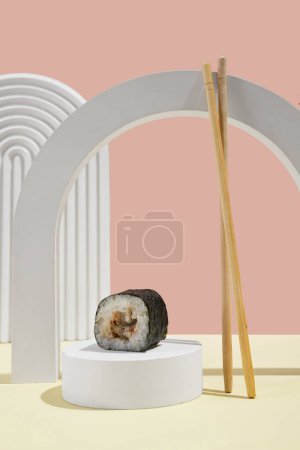 Foto de Cultura asiática, hosomaki japonés (sushi, rollos) con anguila sobre un fondo rosa y amarillo. Cocina oriental, cocina oriental. Sabrosos aperitivos en bandeja y palillos - Imagen libre de derechos