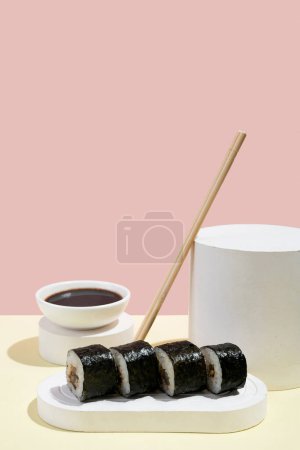 Photo for Asian culture, Japanese hosomaki (sushi, rolls) with eel on a pink and yellow background. Oriental culinary, eastern cooking. Tasty appetizers on platter and chopsticks, soy sauce - Royalty Free Image