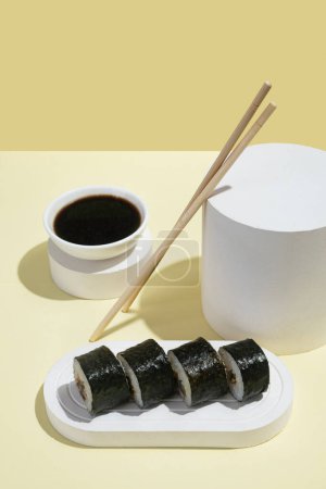 Photo for Asian culture, Japanese hosomaki (sushi, rolls) with eel on a yellow background. Oriental culinary, eastern cooking. Tasty appetizers on platter and chopsticks, soy sauce - Royalty Free Image