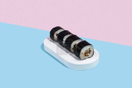 Photo for Hosomaki (sushi) with eel on a white stand on a colorful plain background (blue, pink). A simple concise composition - Royalty Free Image