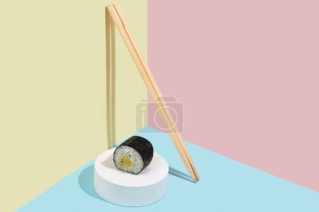 Hosomaki (sushi, bułki) z węgorzem na białym tynku stojak na kolorowym tle gładkiej (niebieski, różowy, żółty). Prosta zwięzła kompozycja