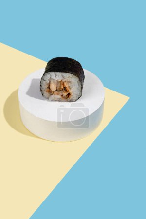 Photo for Hosomaki (sushi, rolls) with eel on a white plaster stand on a multi-colored plain background (blue, yellow). A simple concise composition - Royalty Free Image