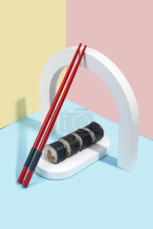 Foto de Hosomaki (sushi, rollos) con anguila sobre un soporte de yeso blanco sobre un fondo liso de colores (azul, rosa, amarillo). Una composición simple y concisa - Imagen libre de derechos