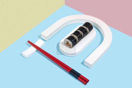 Foto de Hosomaki (sushi, rollos) con anguila sobre un soporte de yeso blanco sobre un fondo liso de colores (azul, rosa, amarillo). Una composición simple y concisa - Imagen libre de derechos