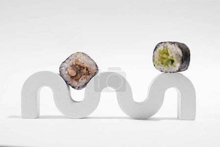 Foto de Hosomaki japonés (sushi, rollos) con anguila sobre un soporte de yeso blanco sobre un fondo liso blanco. Una composición simple y concisa - Imagen libre de derechos