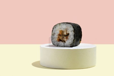 Foto de Cultura asiática, hosomaki japonés (sushi, rollos) con anguila sobre un fondo rosa y amarillo. Cocina oriental, cocina oriental. Sabrosos aperitivos en bandeja - Imagen libre de derechos