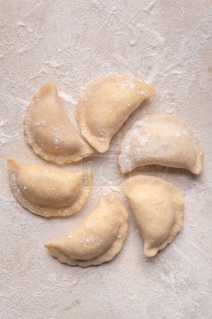 Téléchargez les photos : Fresh dumplings in flour on a light background.Background. Homemade craft production, national traditions, Ukrainian cuisine - en image libre de droit