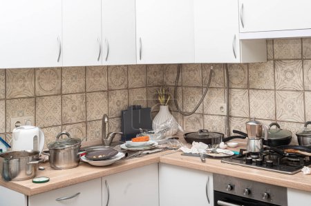 Foto de Cocina desordenada con platos sucios apilados en el fregadero y en el mostrador. Cocina moderna con fachadas blancas al estilo escandinavo - Imagen libre de derechos