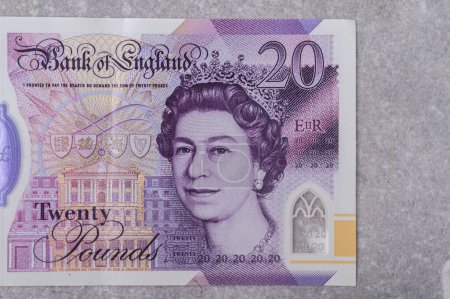 Foto de Moneda de Gran Bretaña (Inglaterra) libra. Billetes con denominación y 20 imágenes del retrato de la reina Isabel sobre fondo gris - Imagen libre de derechos