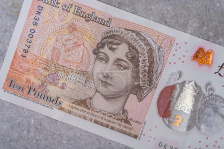 Foto de Moneda de Gran Bretaña (Inglaterra) libra. Billetes en denominaciones de 10 con la imagen de un retrato de Jane Austen sobre un fondo gris - Imagen libre de derechos