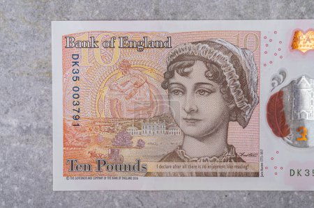 Foto de Moneda de Gran Bretaña (Inglaterra) libra. Billetes en denominaciones de 10 con la imagen de un retrato de Jane Austen sobre un fondo gris - Imagen libre de derechos