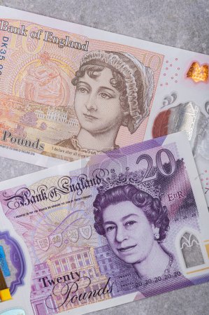 Foto de Moneda de Gran Bretaña (Inglaterra) libra. Billetes en denominaciones y 20 con un retrato de la reina Isabel sobre un fondo gris - Imagen libre de derechos