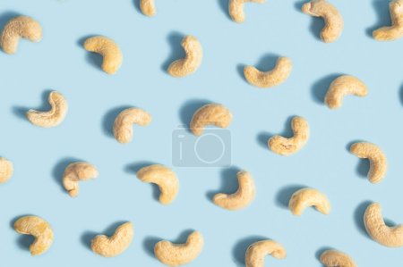 Photo for Cashew nuts against a blue background. This image represents a healthy snack option and can be used to convey concepts like nutrition, veganism, natural food, and wellness. - Royalty Free Image