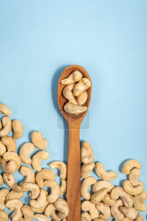 Foto de Anacardos en una cuchara de madera sobre un fondo azul. Esta imagen representa una opción de snack saludable y se puede utilizar para transmitir conceptos como la nutrición, el veganismo, la comida natural y el bienestar.. - Imagen libre de derechos