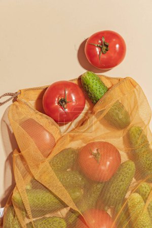 Téléchargez les photos : Sacs réutilisables pour acheter des légumes et des fruits. Sacs avec tomates et concombres. Eco soin, consommation consciente, soin de la nature. Journée mondiale du ravitaillement - en image libre de droit