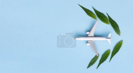 Foto de Combustible de aviación sostenible. Modelo avión blanco, hojas verdes frescas sobre fondo azul. Energía limpia y verde, Biocombustible para la industria aeronáutica. - Imagen libre de derechos