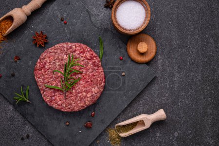 Photo for Juicy raw burger patty against a dark backdrop. Creation is perfect for burger lovers seeking an authentic and flavorful experience - Royalty Free Image