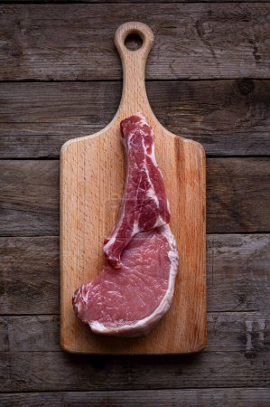 Photo for Indulge in the rustic charm of a raw piece of pork loin on a wooden board. This mouthwatering dish combines savory flavors with a rustic presentation, creating a culinary masterpiece - Royalty Free Image