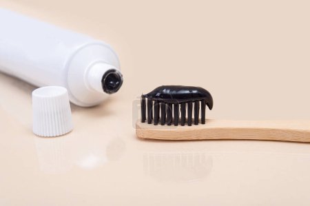 Photo for White tube with black toothpaste and a bamboo brush with black bristles on a beige background. Minimalism. Dental health care - Royalty Free Image