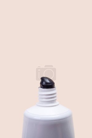 Foto de Tubo blanco con pasta de dientes negra sobre fondo beige. Minimalismo. Atención de la salud dental - Imagen libre de derechos