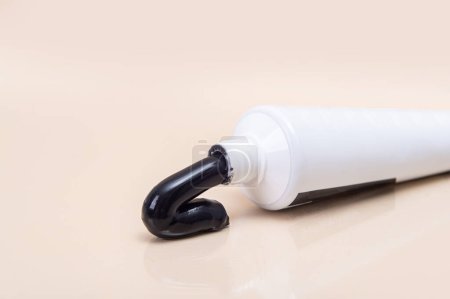 Foto de Tubo blanco con pasta de dientes negra sobre fondo beige. Minimalismo. Atención de la salud dental - Imagen libre de derechos