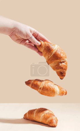 Photo for Fresh delicious croissants are held by a female hand, levitation. Three croissants - Royalty Free Image