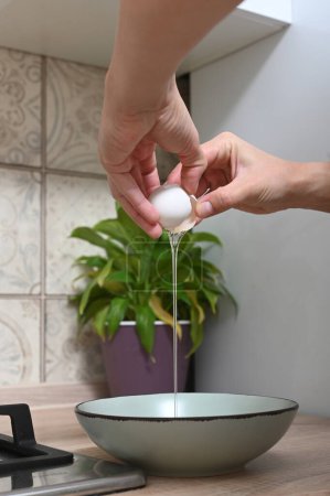 Photo for Woman breaks eggs to make an omelette. Female hands hold a chicken egg. Home cooking, hearty home-made simple dishe - Royalty Free Image