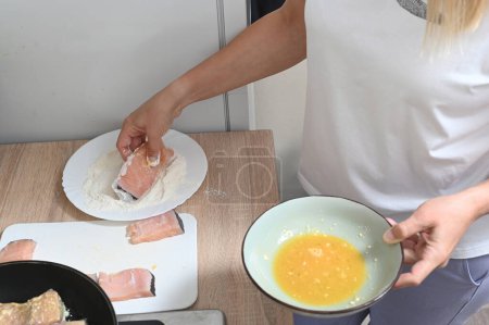 Téléchargez les photos : Women's hands roll pieces of fish in flour and egg batter. home cuisine - en image libre de droit