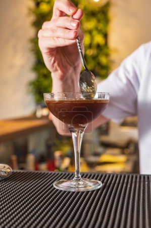 Foto de El camarero detrás de la barra hace un martini expreso. Cóctel con vermut y café - Imagen libre de derechos