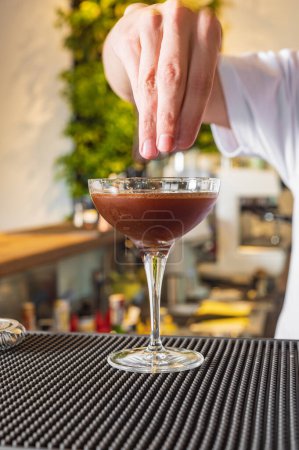 Foto de El camarero detrás de la barra hace un martini expreso. Cóctel con vermut y café - Imagen libre de derechos