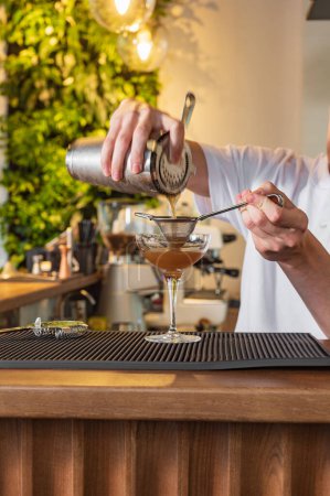 Téléchargez les photos : Le barman derrière le bar fait un martini expresso. Cocktail avec vermouth et café - en image libre de droit